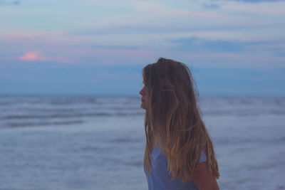 Side view of woman standing against sea during sunset