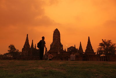 Tourists visiting historic temple in ayutthaya kingdom against sky during sunset