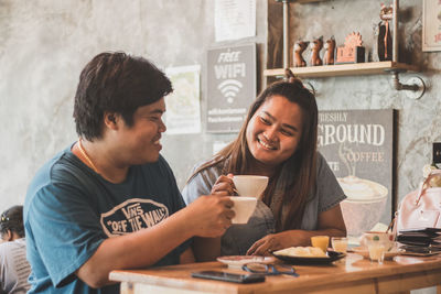 Young man and woman using smart phone in cafe