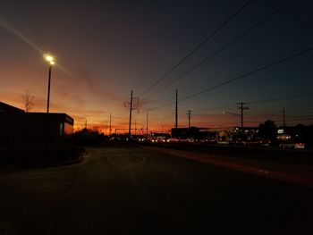 Cars on road against sky at sunset