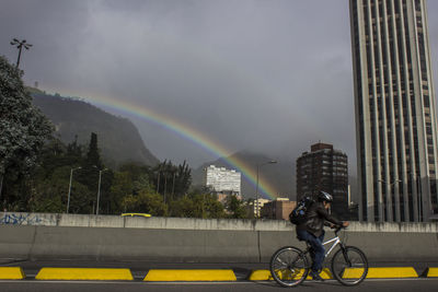 Man riding bicycle on road against city