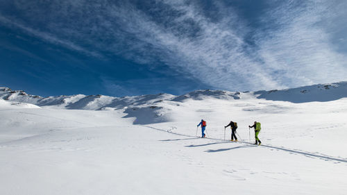 People skiing on snowcapped mountain against sky