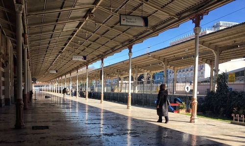 People at railroad station in city against sky