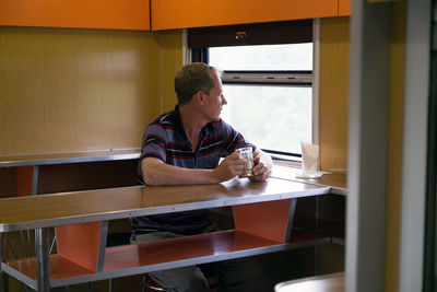 Man looking away while sitting on table in restaurant