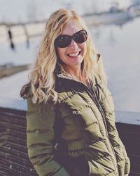 Portrait of smiling mature woman wearing warm clothing while standing against river