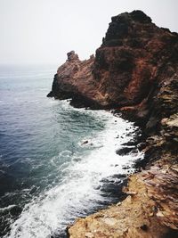Rock formation in sea against clear sky