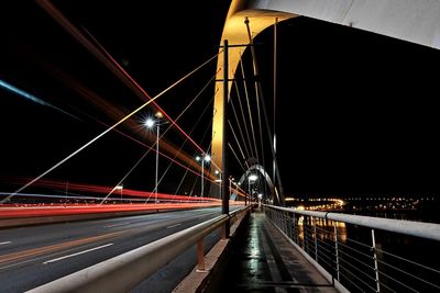 Light trails on suspension bridge against sky at night