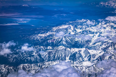 Aerial view of snowcapped mountains against blue sky