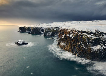 Snowy cliff and breaking waves in winter