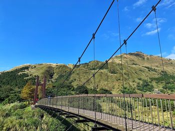 Bridge over mountain against blue sky