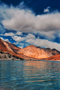 Scenic view of lake by mountains against sky