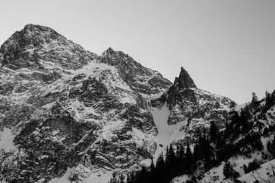 Low angle view of snowcapped mountains against clear sky