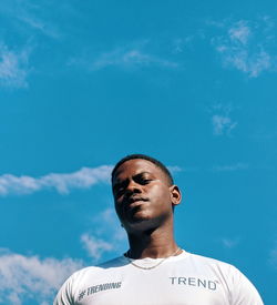 Low angle portrait of young man against blue sky