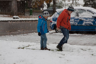 Full length of boys playing on snow covered street