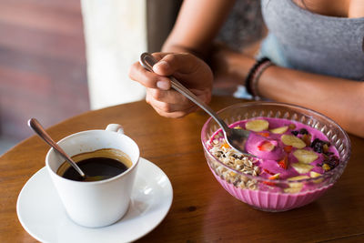 Midsection of woman with coffee cup on table