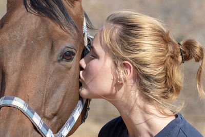 Close-up of young woman kissing horse