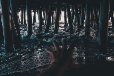 Cropped image of woman reaching pier over sea