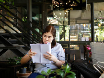Woman reading book while sitting in cafe