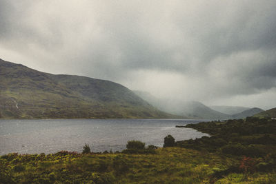 Scenic view of lake by mountain against sky