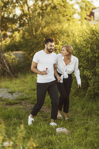 Smiling young couple talking while walking on grassy field