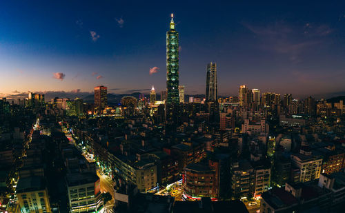 Illuminated buildings in city against sky at night