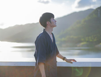 Side view of young man standing on lake