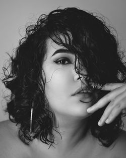 Black and white photo of a woman with curly hair looking to the camera hand on her face