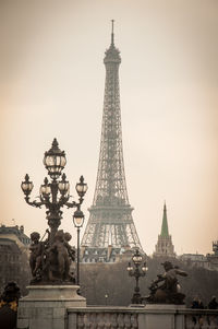 Antique street light with statue in front of eiffel tower against sky