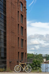 Bicycle parked by building against sky