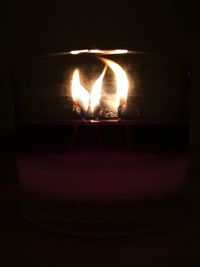 Close-up of lit candle against black background