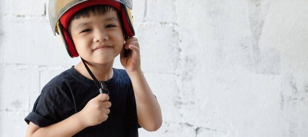 Portrait of smiling boy standing against wall