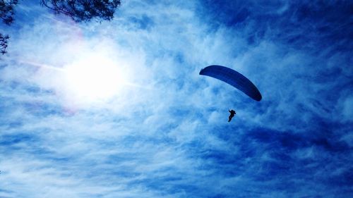 Low angle view of silhouette person paragliding against sky