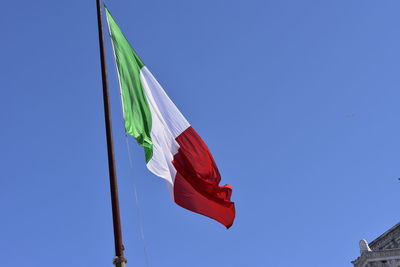 Low angle view of flag against clear blue sky