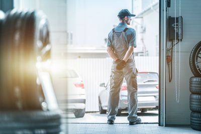 Rear view of male mechanic standing in auto repair shop