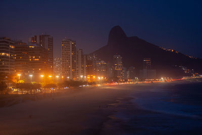 Illuminated buildings in city against sky at night
