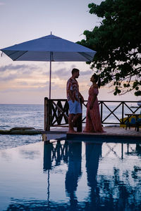 Man and woman standing at swimming pool against sky