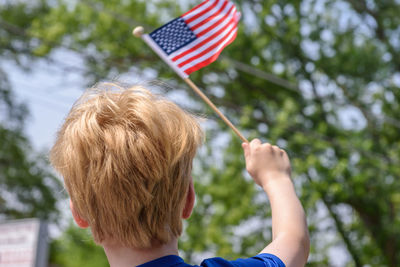 Boy with flag against trees