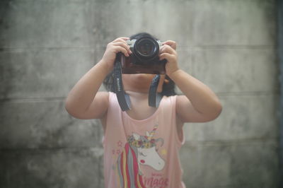 Midsection of woman photographing against wall