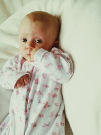 High angle view of baby girl looking up while lying on bed