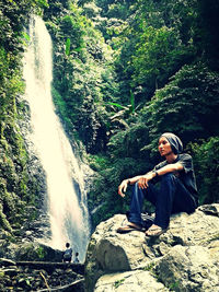 Woman sitting on rock in forest