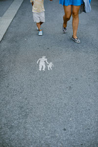 Low section of mother with child walking on road