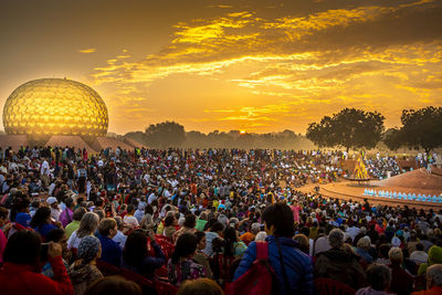 Crowd at music concert against sky during sunset