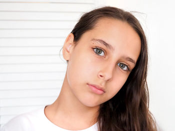 Close-up portrait of a young woman against wall