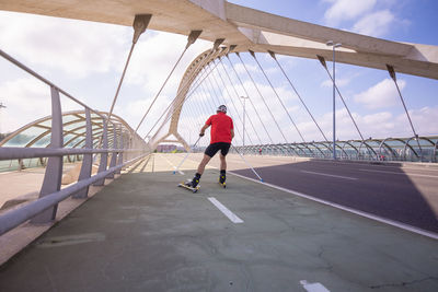 Rear view of athlete ski rolling on bridge