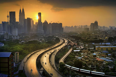 Road and modern buildings against sky during sunset