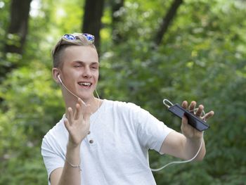 Young man with headphones dancing in forest