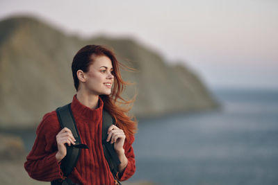 Young woman looking away while standing in sea