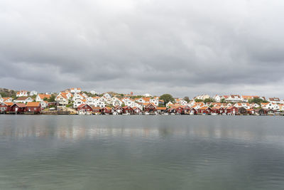 Illuminated buildings by sea against sky