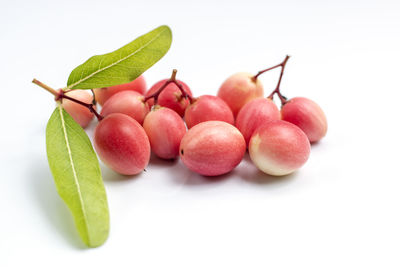 Close-up of fruits and leaves against white background