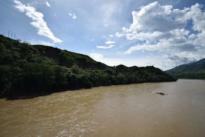 View of river amidst mountains against sky